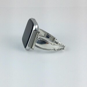 Peut inclure: Une montre connect&eacute;e argent&eacute;e avec un bracelet en m&eacute;tal argent&eacute;. Le bracelet est fait &agrave; partir d'une pi&egrave;ce de couverts r&eacute;utilis&eacute;e.