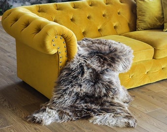 Può includere: Un divano in velluto giallo con bottoni e due cuscini in velluto giallo e una coperta in pelliccia sintetica marrone sul pavimento di fronte ad esso.