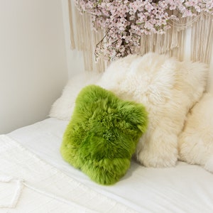 Peut inclure: Un lit blanc avec une couverture blanche et moelleuse et trois oreillers. Deux des oreillers sont blancs et moelleux, et un est un oreiller moelleux vert vif.