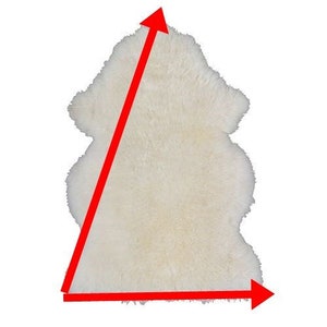 May include: White sheepskin rug with a triangular shape. The rug is approximately 3 feet wide and 4 feet long.