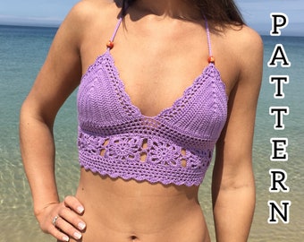May include: A purple crochet bikini top with a scalloped edge and orange beads. The top is worn by a person on a beach.