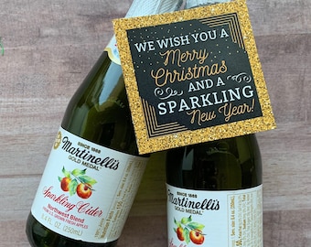 Puede incluir: Dos botellas de vidrio verde de sidra espumosa Martinelli's con una etiqueta dorada brillante que dice "We wish you a Merry Christmas and a Sparkling New Year!". Las botellas son de 250 ml cada una.