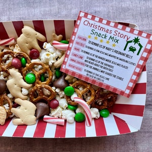 May include: A Christmas Story Snack Mix in a red and white striped container. The mix includes popcorn, pretzels, M&Ms, candy canes, animal crackers, and Hershey Kisses. A card explains the symbolism of each snack item.