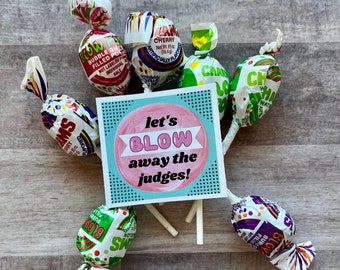 May include: A blue and white card with the text "let's blow away the judges!" surrounded by colorful lollipops. The lollipops are red, green, and purple with white stripes.