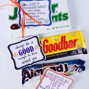 K&ouml;nnte beinhalten: Drei Geschenkverpackte Schokoladenriegel mit bunten Anh&auml;ngern. Die Anh&auml;nger haben inspirierende Botschaften, wie "Dein Engagement f&uuml;r das Evangelium wird dein Leben f&uuml;r immer segnen." und "Sei immer ein gutes Vorbild f&uuml;r diejenigen, die dich umgeben."