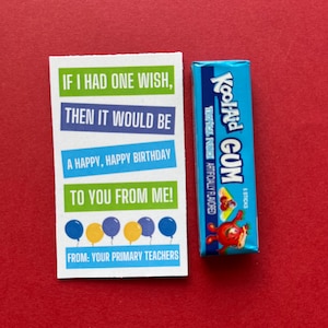May include: A birthday card with the message "If I had one wish, then it would be a happy, happy birthday to you from me!" and a blue and yellow balloon design. Next to it is a blue package of Kool-Aid gum.