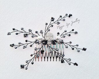 May include: Black hair comb with three silver skull charms and black beads. The comb is decorated with black crystals and has a black wire design. The text "Maggie Lyn Jewellery" is visible in the upper right corner of the image.