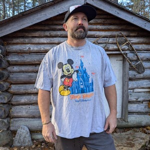 May include: A gray t-shirt with a Mickey Mouse graphic and the text "Magic Kingdom" and "Walt Disney World".