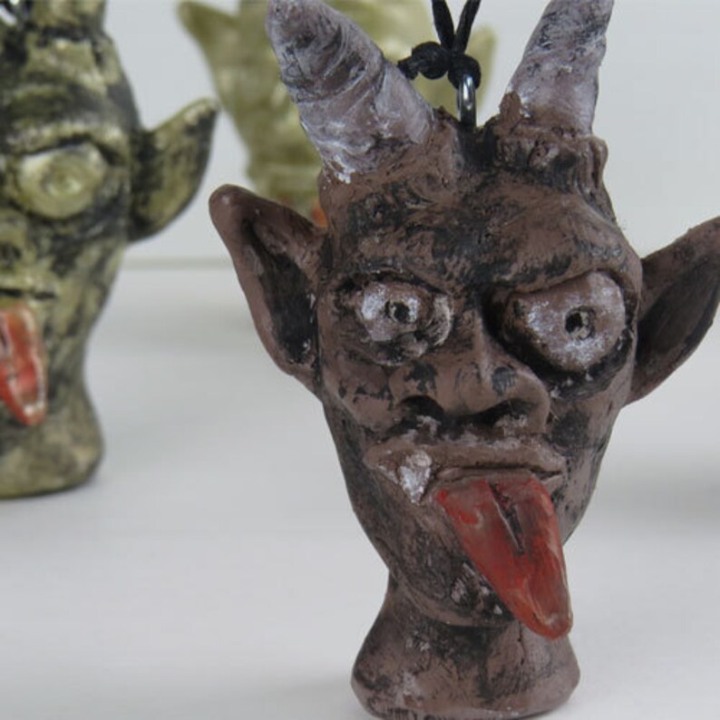 Peut inclure: Une figurine en c&eacute;ramique brune repr&eacute;sentant un diable avec des cornes, une longue langue et une expression espi&egrave;gle. La figurine est peinte avec des d&eacute;tails noirs et blancs et a une surface textur&eacute;e.