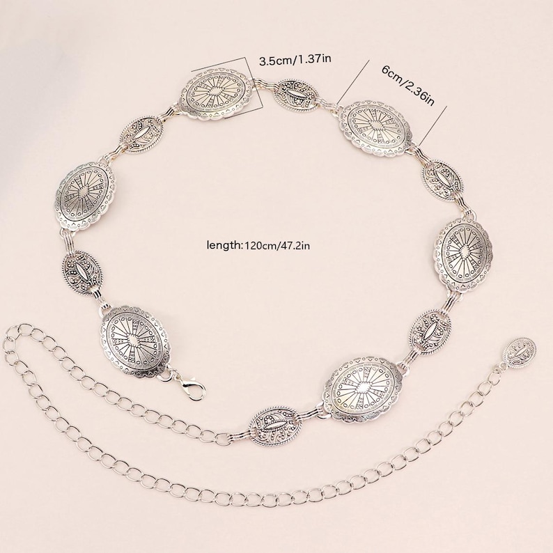 May include: Silver metal belt featuring oval and oblong decorative elements. The belt is 120cm long, with oval pieces measuring 6cm. The belt has a chain extension and a clasp closure. The decorative elements have a detailed, engraved design.