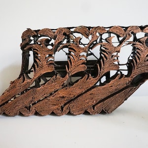 May include: A vintage wooden printing block with a carved design of stylised leaves and flowers. The block is made of dark brown wood and has a worn, rustic appearance.