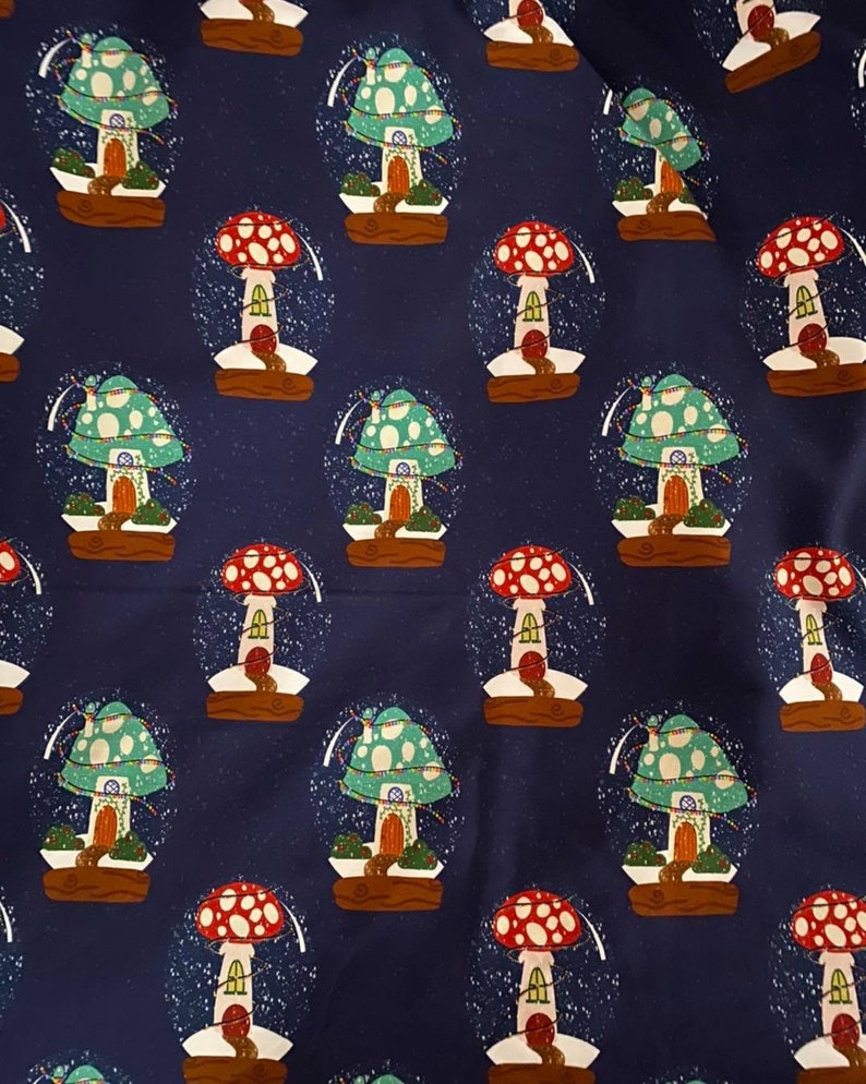 May include: A repeating pattern of whimsical snow globes on a navy blue background. Each globe features a mushroom house with a red or green cap, a brown base, and a dusting of white snow. The design is playful and fantasy-themed.