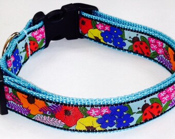 May include: A blue dog collar with a floral and ladybug print. The collar is made of nylon and has a plastic buckle.