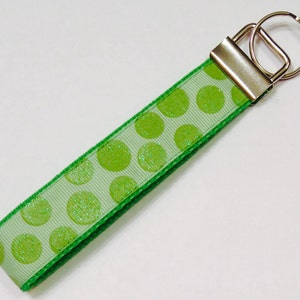 May include: A green and white polka dot key chain with a silver key ring.