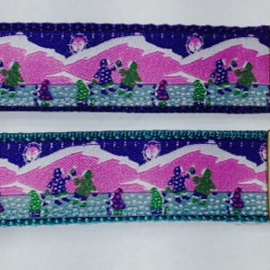 May include: Two purple and teal keychains with a pink and blue mountain scene and a silver key ring.