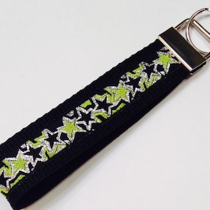 May include: Black key chain with a silver and green star pattern.