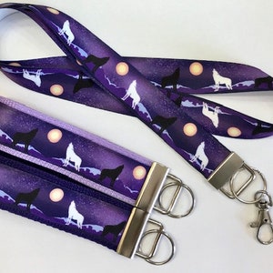 May include: Two purple and white wolf patterned keychains with silver key rings and a matching purple and white wolf patterned lanyard with silver hardware.