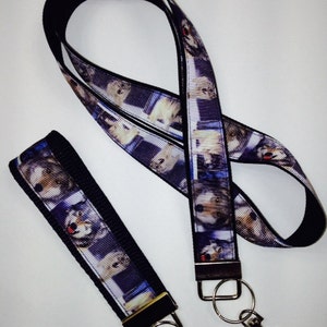 May include: A black and white wolf print lanyard with a black breakaway clasp and a silver key ring. The lanyard is made of a soft, durable fabric and is perfect for holding keys, ID badges, or other small items.