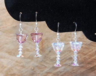 May include: Four pairs of dangle earrings with crystal wine glass charms. Two pairs are clear and two pairs are a light pink color.