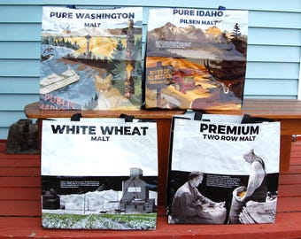 May include: Four reusable shopping bags with black handles. The bags feature graphics and text: "Pure Washington Malt," "Pure Idaho Pilsen Malt," "White Wheat Malt," and "Premium Two Row Malt." The bags have colorful landscape and black and white imagery.