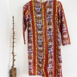 May include: A vintage dress with a long sleeve and a colorful floral and geometric pattern. The dress is made of a lightweight fabric and has a relaxed fit.