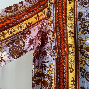 May include: A long-sleeved shirt with a paisley pattern in shades of brown, orange, yellow, and white on a light purple background.
