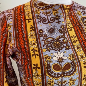 May include: A long-sleeved shirt with a vintage floral pattern in shades of brown, orange, yellow, and blue. The pattern features flowers, leaves, and swirls.
