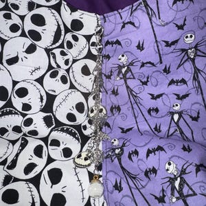 May include: A split-design fabric featuring a black and white skull pattern on one side and a purple pattern with Jack Skellington and bats on the other. A decorative chain with skull charms and a clear orb hangs from the center.