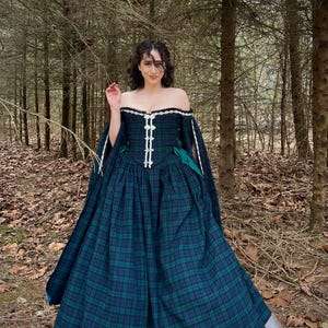 Könnte beinhalten: Ein dunkelblau-grünes, kariertes schulterfreies Kleid mit weißer Bordüre und weitem Rock. Das Kleid hat ein eng anliegendes Oberteil mit weißen Knöpfen und langen, fließenden Ärmeln. Der Rock ist über einem weißen Petticoat geschichtet.
