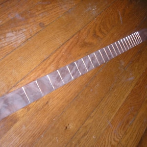 May include: A long, thin, wooden fretboard with 18 frets. The fretboard is made of a light-colored wood and has a smooth, polished finish.