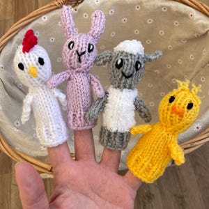 May include: Four knitted finger puppets in a basket. The puppets are a pink bunny, a white chick, a gray sheep, and a yellow chick.