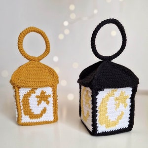 May include: Two crocheted lanterns, one yellow and one black, with a white crescent moon and star design. The lanterns have a loop at the top for hanging.