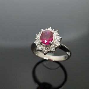 以下が含まれることがあります： 大きな楕円形のルビーを小さなダイヤモンドで囲んだシルバーリング