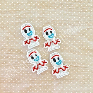 May include: Four white felt Forky character patches with red, blue, and black details. Each patch features a smiling face, red arms, and a red zig-zag design. The patches are arranged on a light brown surface with a white heart pattern.
