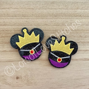 May include: Two black mouse-shaped patches with gold crowns, purple accents, and red jewels. The patches have a glittery texture and are set against a light wood grain background. The text "Lots of Love Stitches" is visible.