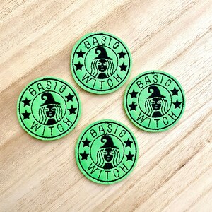 May include: Four circular embroidered patches in light green with black stitching. Each patch features a central graphic of a figure wearing a witch hat, surrounded by the text "BASIC WITCH" and four small stars arranged in a circular border.