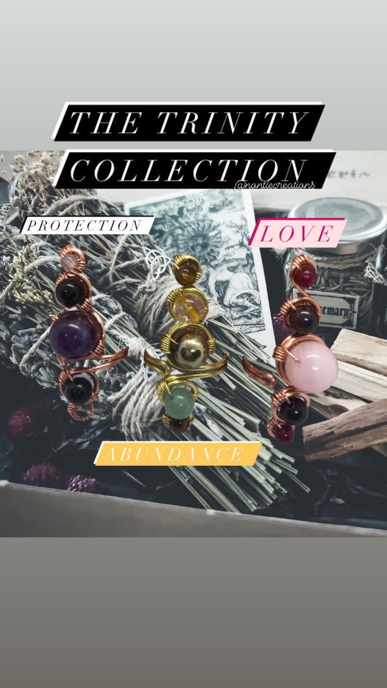 May include: Three wire-wrapped rings with different colored stones. The rings are labeled "Protection", "Love", and "Abundance".
