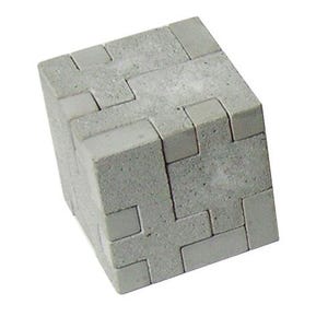 Pode incluir: Um quebra-cabeça de cubo cinza composto por várias peças retangulares intertravadas. O objeto apresenta uma superfície texturizada semelhante a pedra com costuras visíveis onde os componentes individuais se encaixam para formar uma forma sólida.