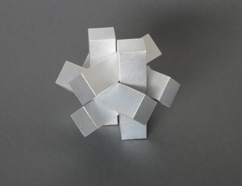 May include: A silver metal puzzle made of six pieces that interlock to form a star shape.