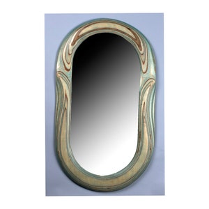 May include: A decorative oval mirror with a unique, wavy, wood frame. The frame is painted in shades of blue, green, and brown.