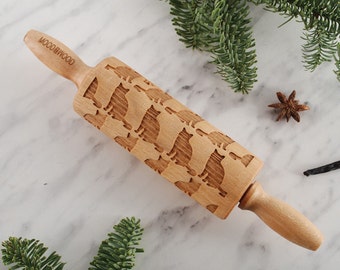 May include: A wooden rolling pin with a carved design of multiple cats. The rolling pin is engraved with the text "WOODGOOD".