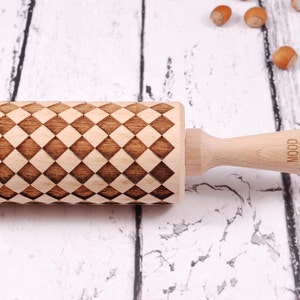 Puede incluir: Un rodillo de madera con un patrón de cuadros grabado en la superficie. El rodillo tiene un mango de madera con el texto "WOOD MOOD" grabado en él.
