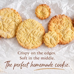 Puede incluir: Varias galletas doradas con dise&ntilde;os florales dispuestas sobre papel pergamino blanco. Las galletas tienen un dise&ntilde;o en relieve detallado y son de varios tama&ntilde;os. El texto de la imagen dice: "Crispy on the edges. Soft in the middle. The perfect homemade cookie."