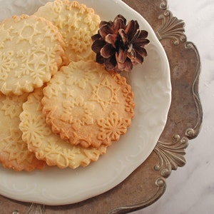 Several round well baked cookies with snowflake design embossed on them.