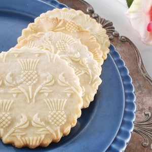 A round well baked cookies with embossed design are lying on a dark blue plate.