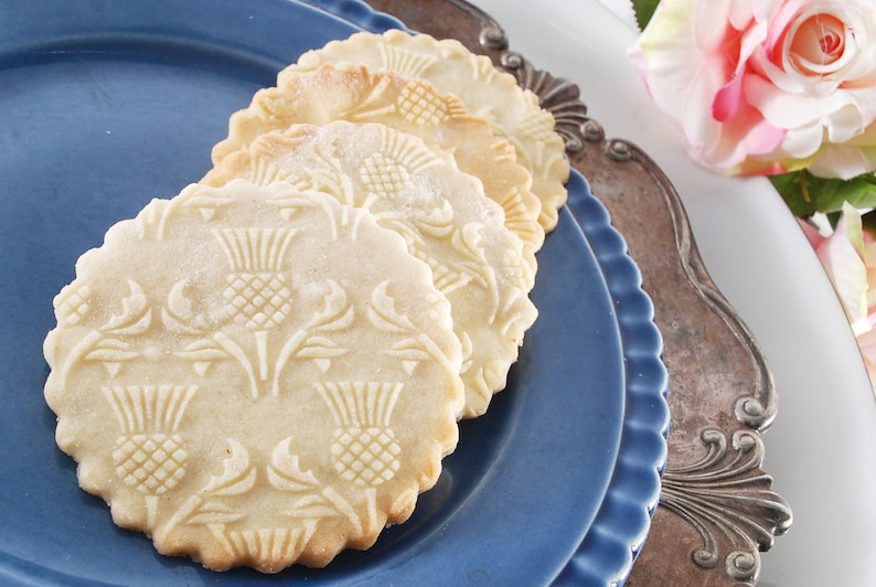 A round well baked cookies with embossed design are lying on a dark blue plate.