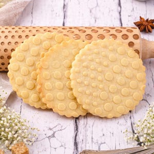 Könnte beinhalten: Ein Set aus drei Keramikbechern mit gesprenkelter, matter Oberfläche. Die Becher sind in Creme-, Hellbraun- und Dunkelbrauntönen gehalten. Jeder Becher hat ein schlichtes, minimalistisches Design.