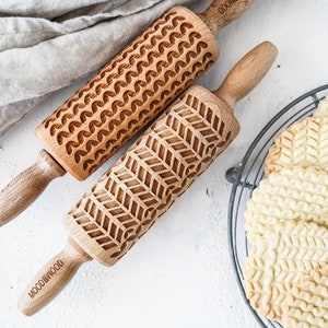 Set of two mini rolling pins with knitt stiches design. Several cookies with embossed design are on a metal trivet.