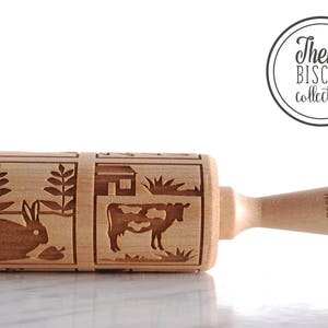 Wooden rolling pin laser engraed to make biscuits with different animal designs. Cow and rabbit are at the front.