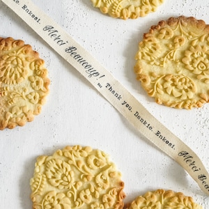 Several well baked cookies with polish folk traditional design are on the white background. A cotton ribbon with "thank you" text in different languages is going across the photo.